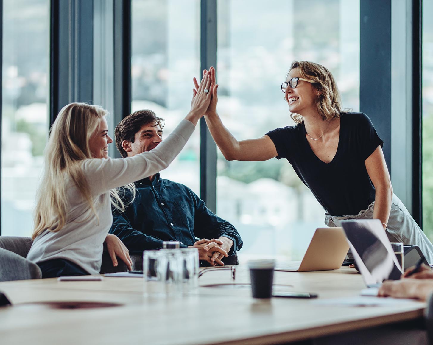 Two women give each other a high five in a meeting
